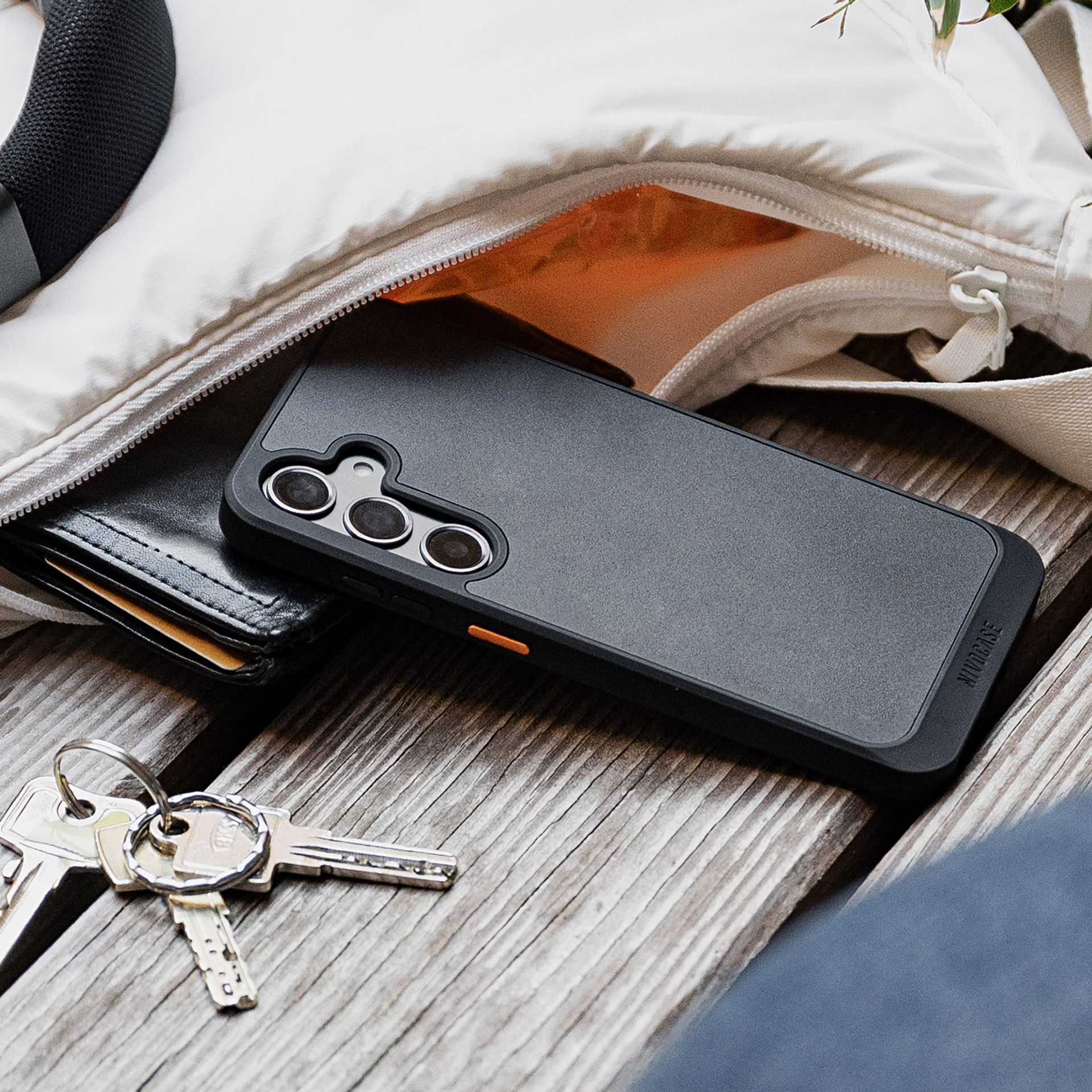 NIVOcore Handyhülle auf einer Holzbank mit Handtasche und Schlüssel in einer urbanen Umgebung.