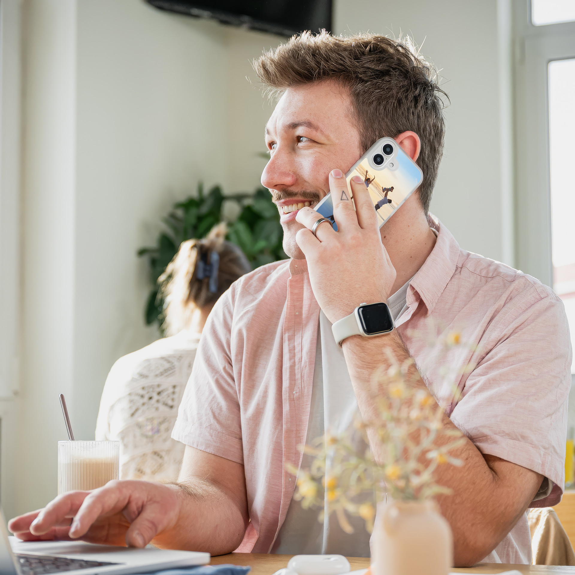Mann telefoniert im Café mit selbstgestalteter Handyhülle